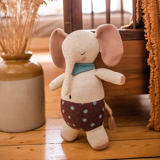 Ein Plüschelefant mit gepunkteten Shorts und blauem Schal.