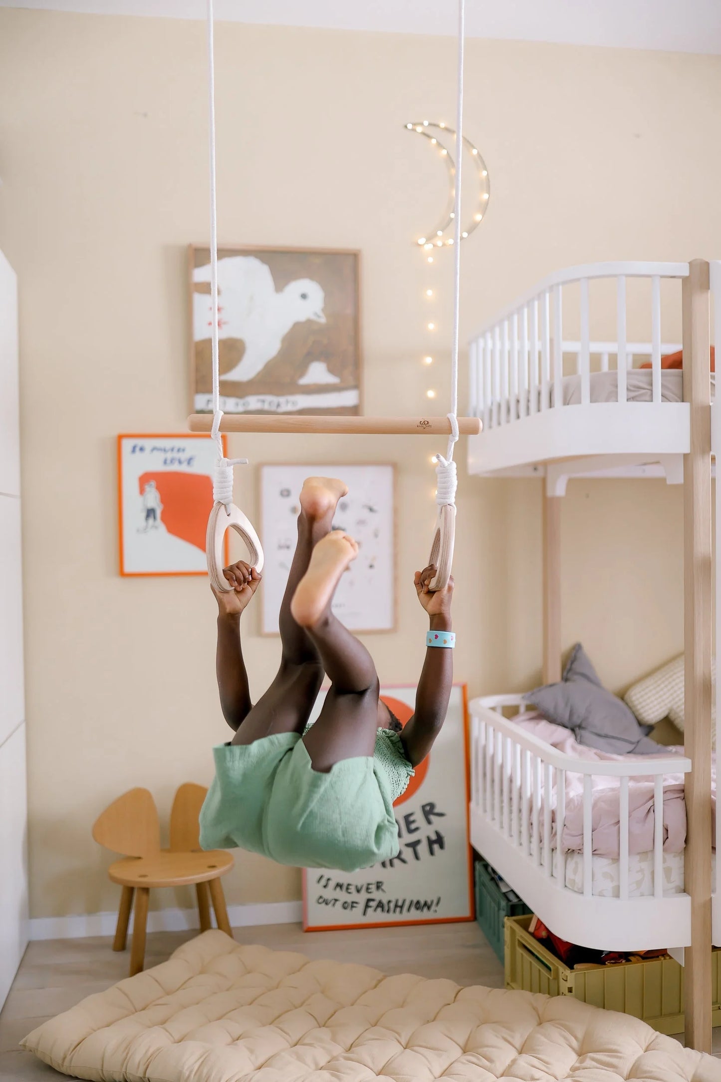 Eine Person in einem mintgrünen Hemd macht einen Handstand gegen eine Wand.