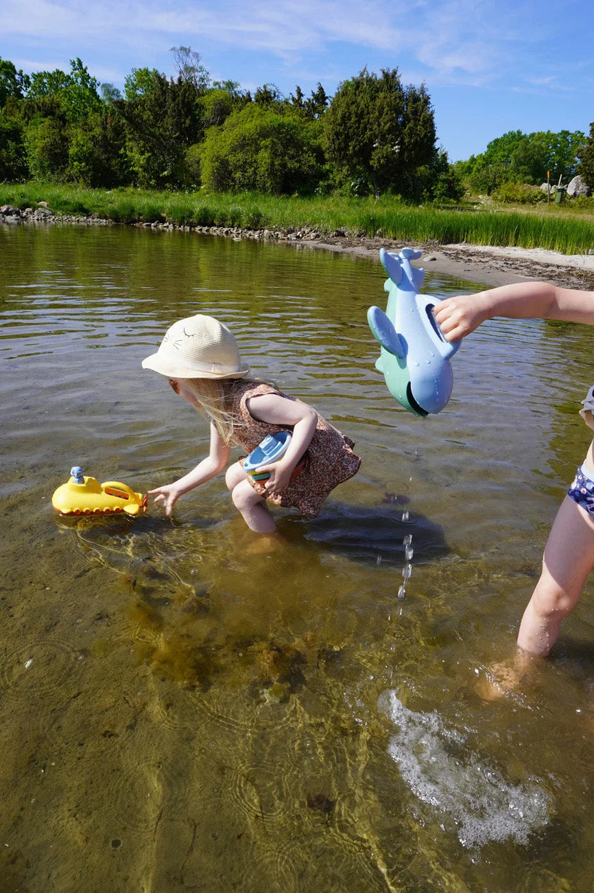 Spielende und planschende Menschen im flachen Wasser des Sees.